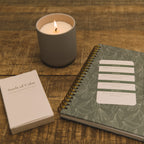 Candle, notebook, and Seeds of Calm card on a wooden surface
